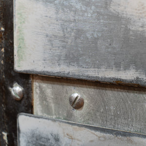 A close up showing the white, distressed metal of a refurbished hospital cart. 