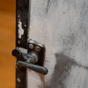 A close up of a steel handle on the cabinet of a refurbished hospital cart. 