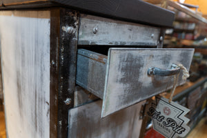 A vintage white metal end table with the top drawer extended. 
