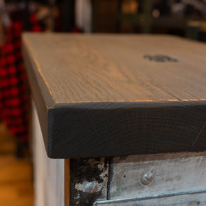 A close up that shows the end grain of a metal cabinet with a wooden top. 