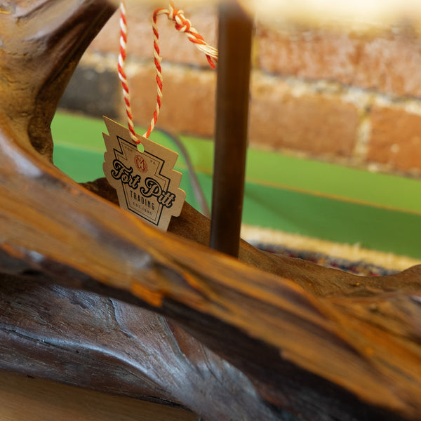 Close up of the Fort Pitt Trading tag hanging on a rustic log lamp.