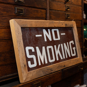 A side view of a vintage brown "No Smoking" sign.
