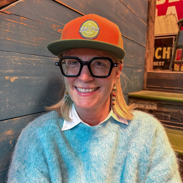 Person wearing an orange and green cap with a Fort Pitt Trading logo